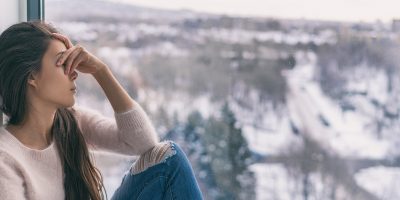 Winter depression sad woman with Seasonal affective disorder girl grief stricken alone at home window thinking negative thoughts. Mental health banner panorama background.